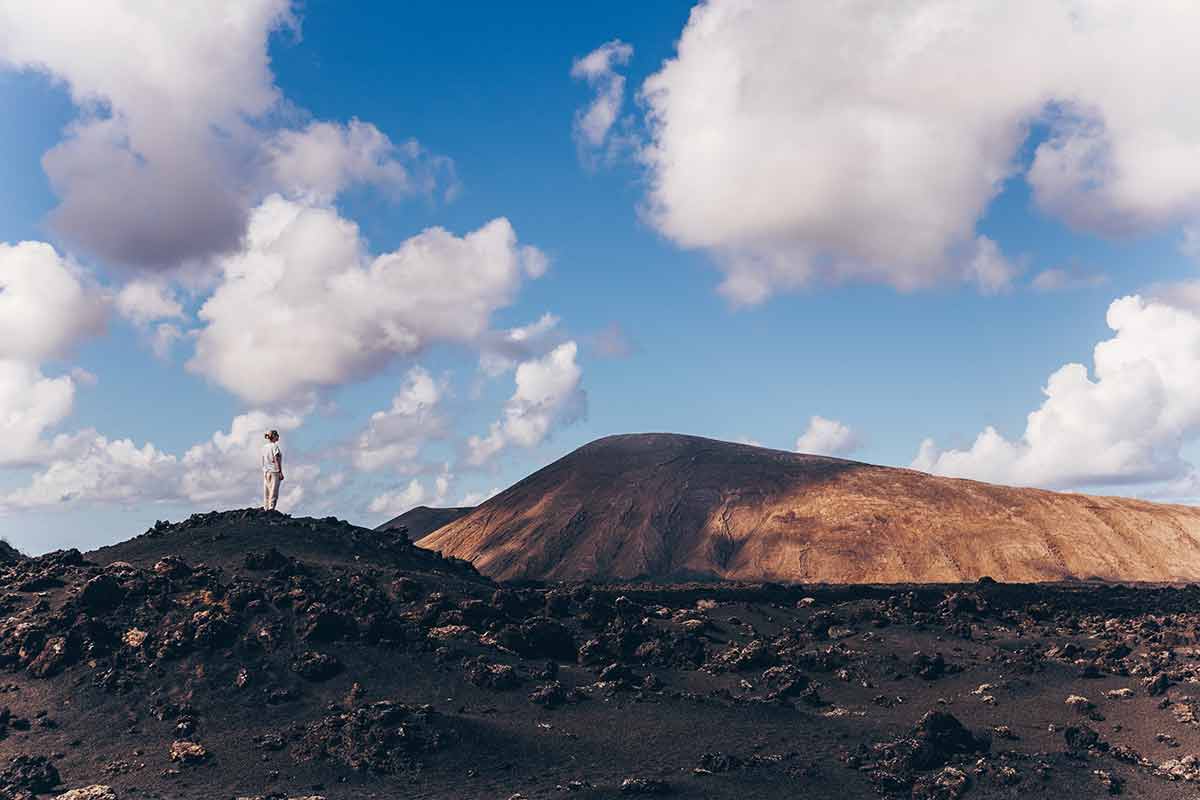 10 best things to do in lanzarote woman rising hands up in the sky, enjoying amazing views of volcanic landscape in Timanfaya national park