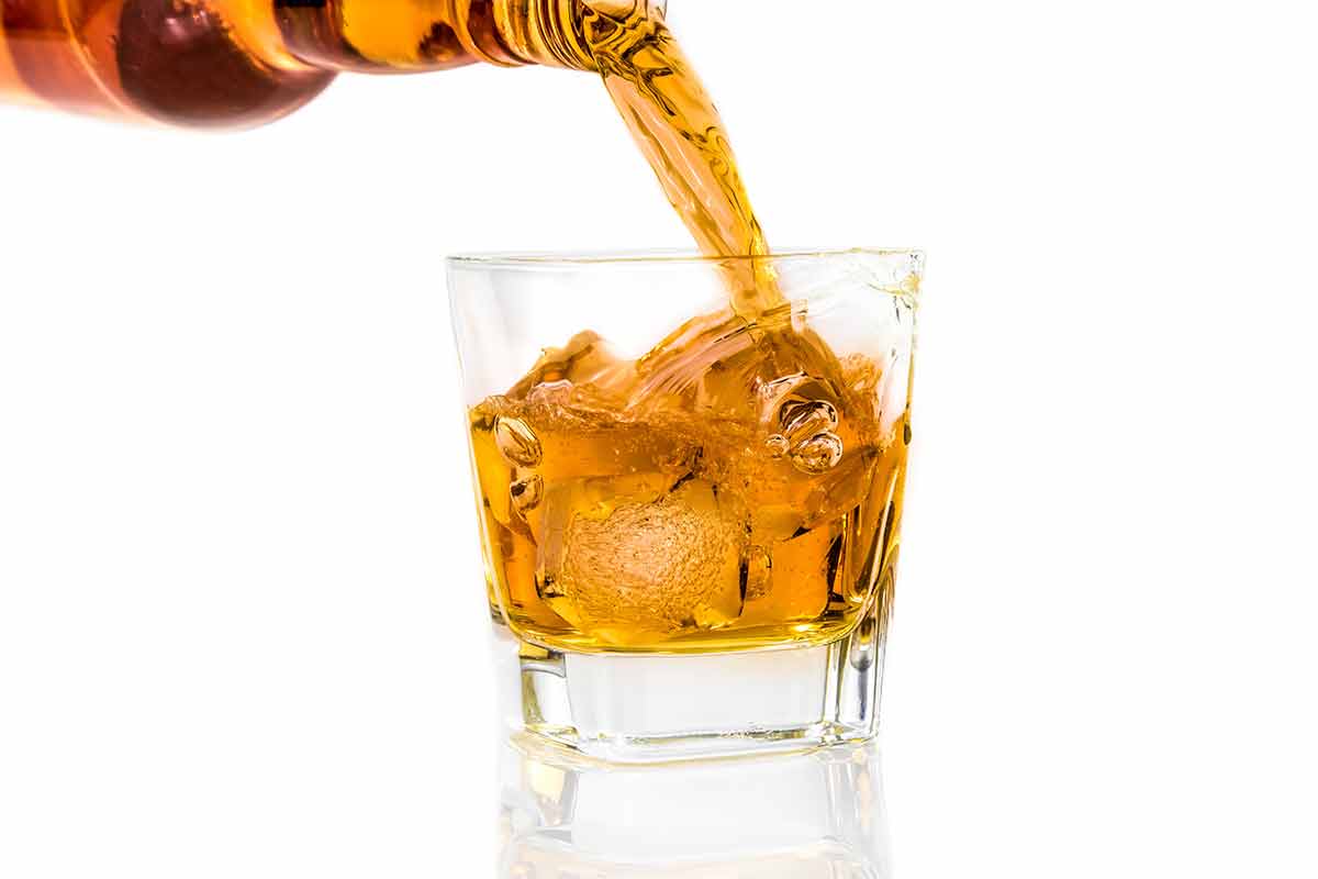 American drinks whiskey being poured into a glass with white background
