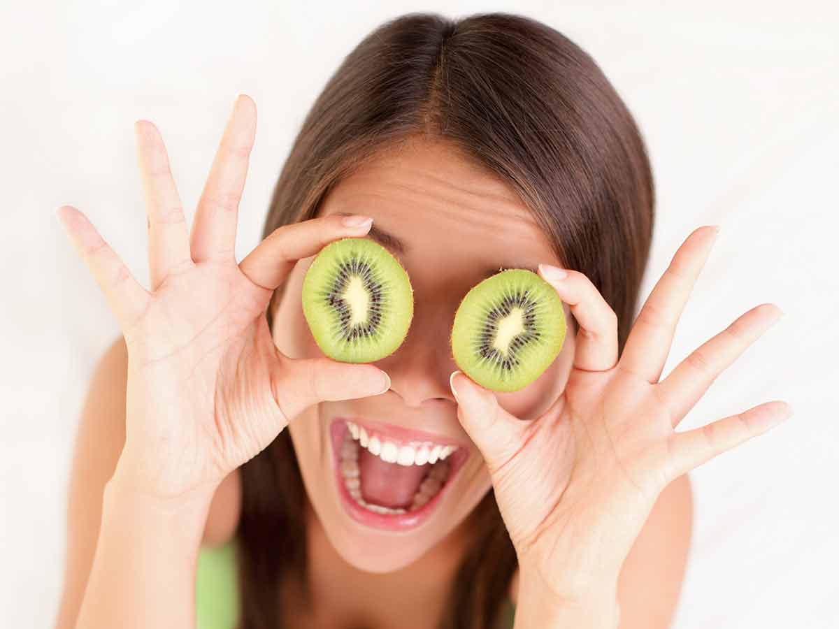 Healthy fruit funny woman holding kiwi fruit for her eyes.
