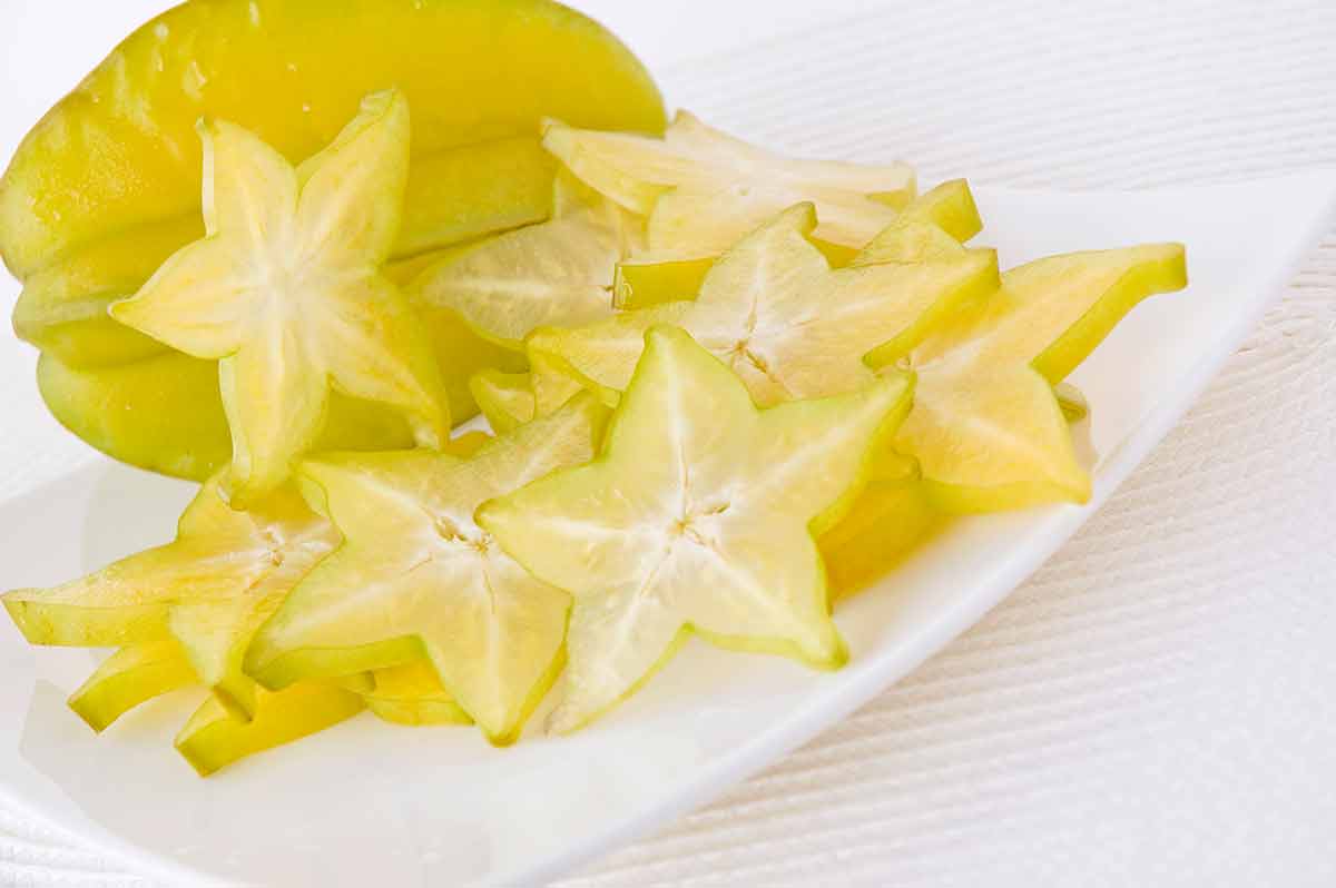 Fresh star fruit and sliced starfruit on white plate