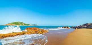 Bai Xep Beach with blue sky, deep golden sand and waves breaking on the rocks