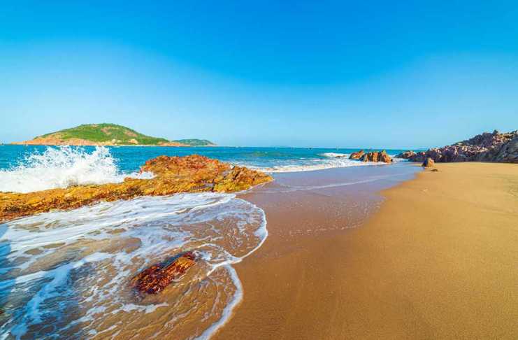 20 Beach Resorts in Vietnam Bai Xep Beach with blue sky, deep golden sand and waves breaking on the rocks