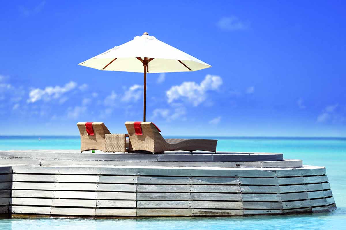 Baros Maldives two luxurious beach lounges under an umbrella on a pontoon