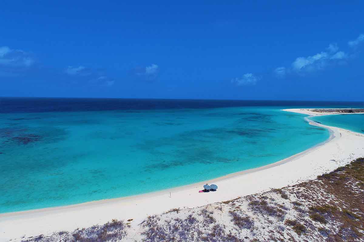 Beaches in South America los roques venezuela white sand and emerald water with two beach umbrellas seen from above