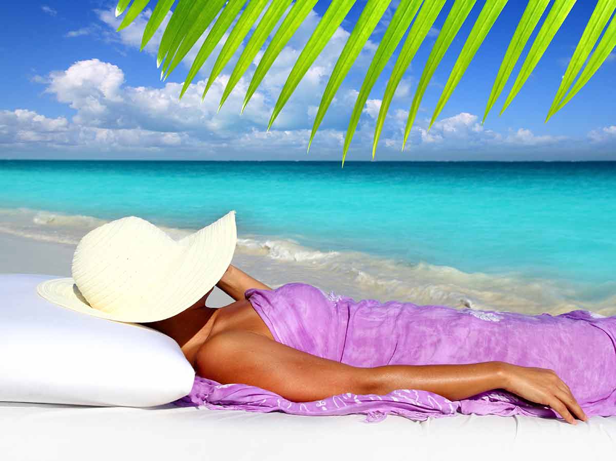 Best beaches in Venezuela woman in sarong lying on a sand with hat covering her face