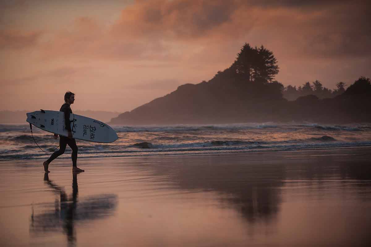 Canada spring surfing in Tofino, a surfer walking the beach at dusk