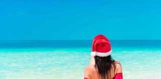 Christmas pictures on the beach Young woman enjoying the sun sunbathing of young woman with santa hat in the ocean .