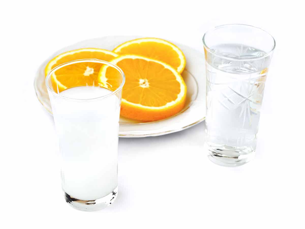 Greek drinks double raki two shots and a plate of sliced oranges