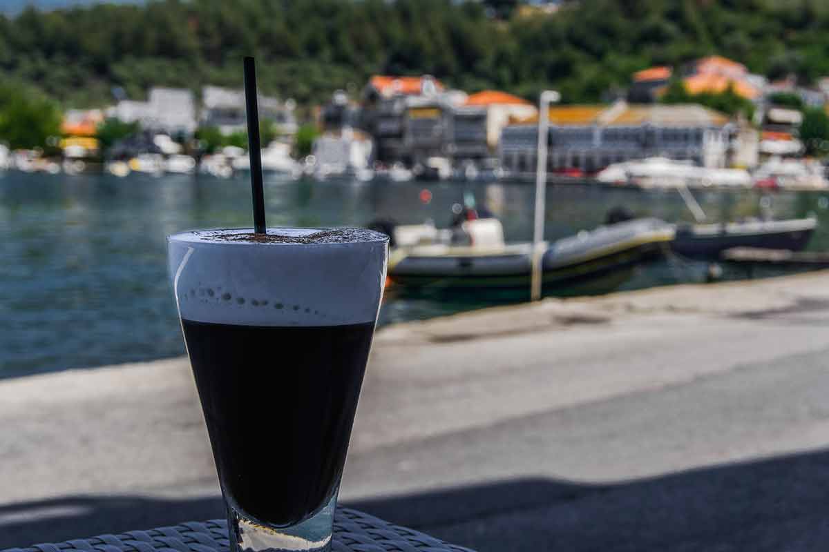 Greek drinks freddo cappuccino coffee with a black straw in a glass