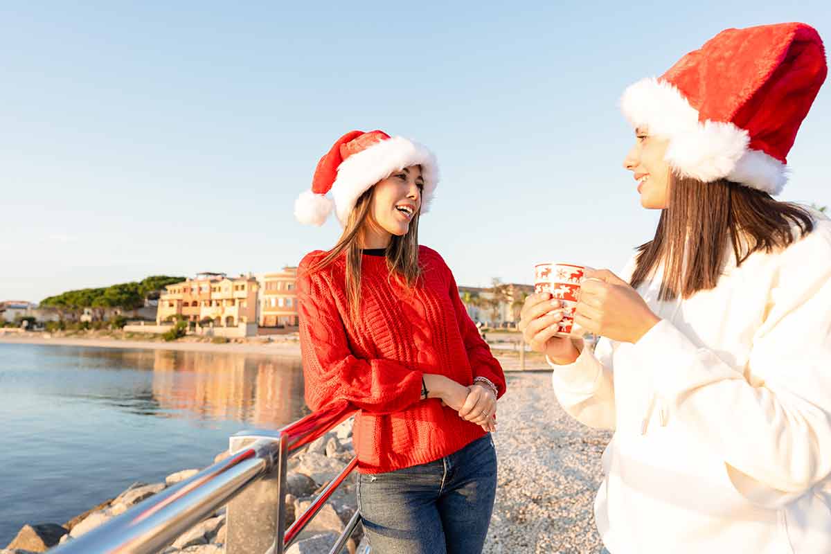 Italy winter two girls chatting by the water wearing santa hats