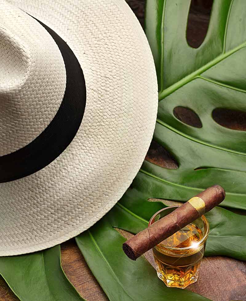 Jamaican Rum cigar balanced across a glass of run and a straw hat