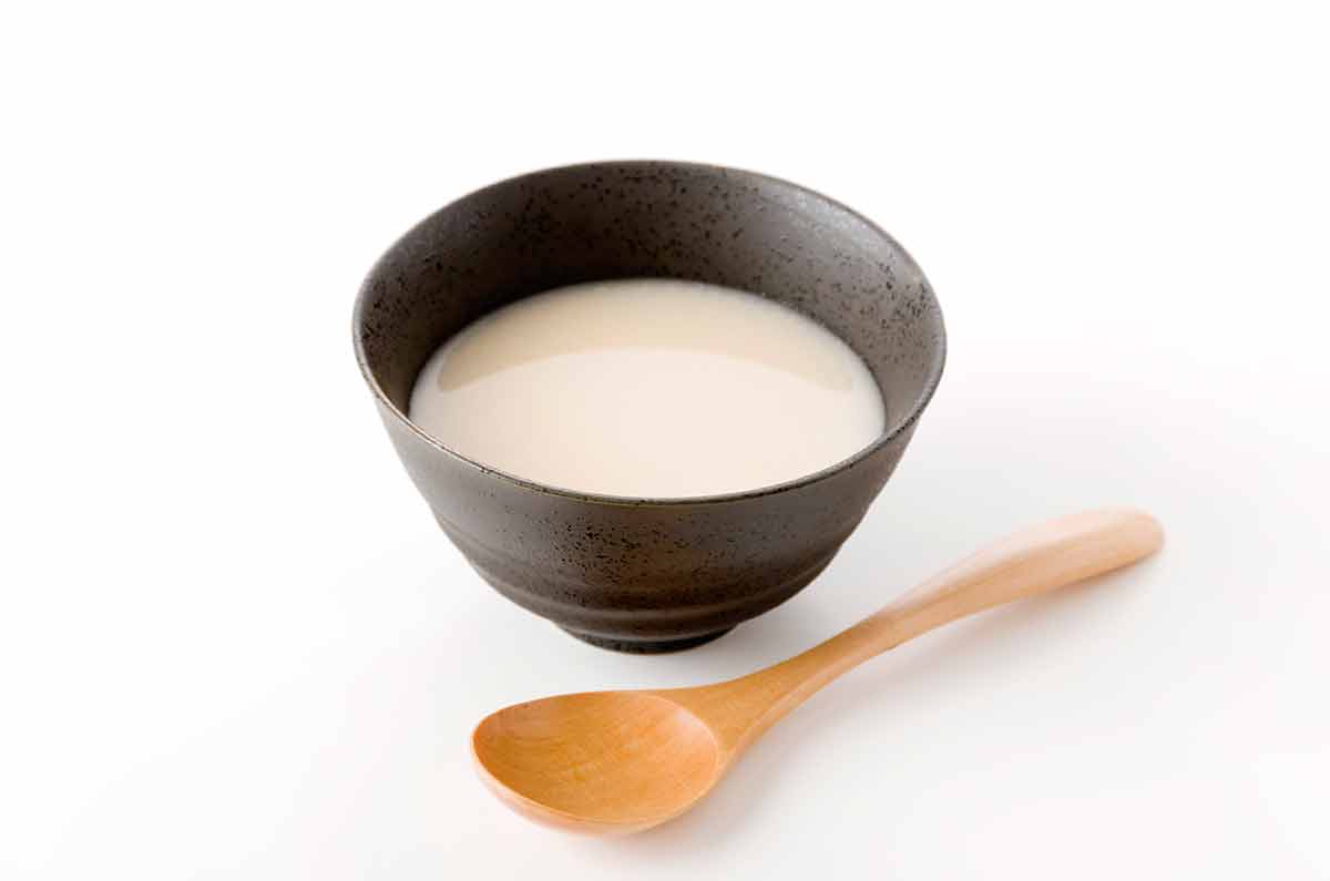 Japanese rice drinks amazake bowl with wooden spoon on a white background