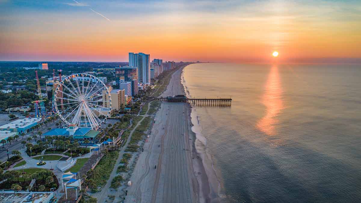 Landmarks in South Carolina Myrtle Beach at sunset with high rise buildings and Ferris wheel
