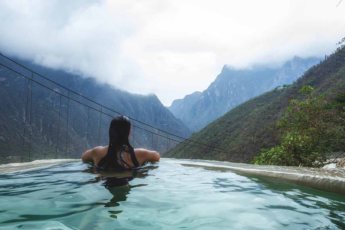 back of woman in a pool gazing at the mountains Las Grutas de Tolantongo