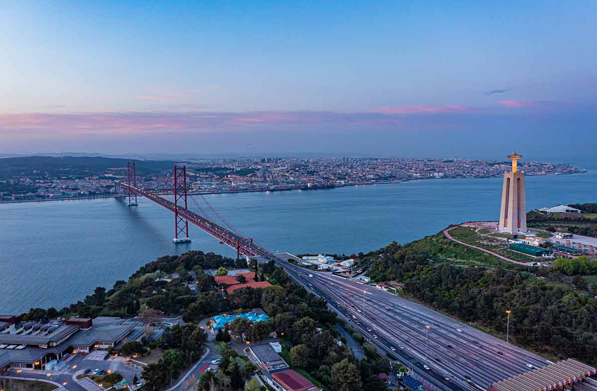Lisbon at night Tagus River Aerial view of multilane road leading on suspension bridge over Tagus river in twilight