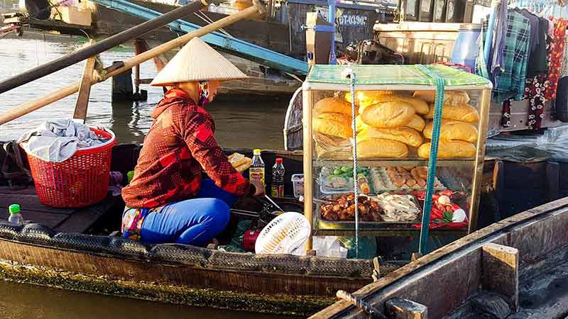 A Street Food Vendor Selling Banh Mi In A Wooden Boat