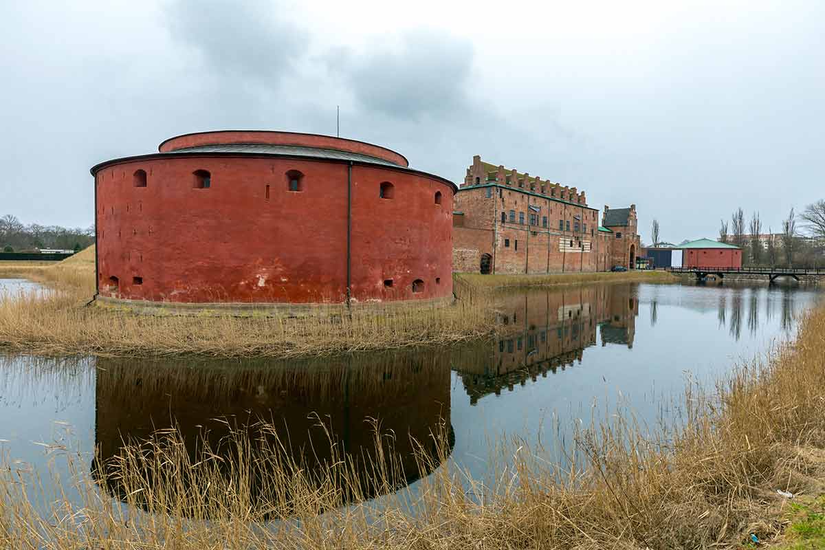 Malmo Castle Sweden with rusty red round building and water in the foreground
