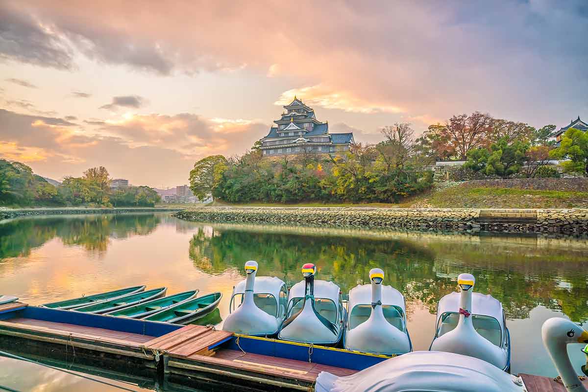Okayama castle in Japan with swan boats in forground