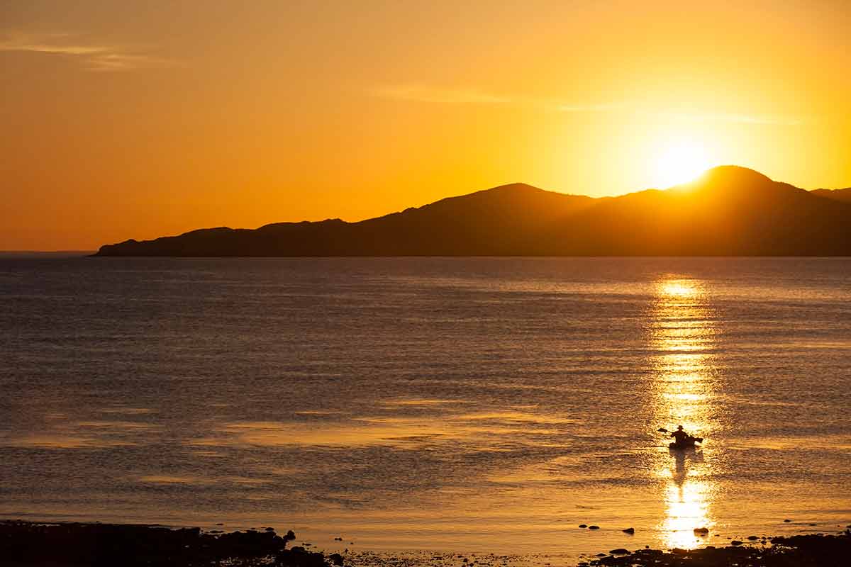 States of Mexico Baja California silhouette of man in kayak with a golden sunrise