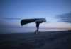 Warmest beaches in Canada man carrying a canoe at dusk on Wasaga Beach