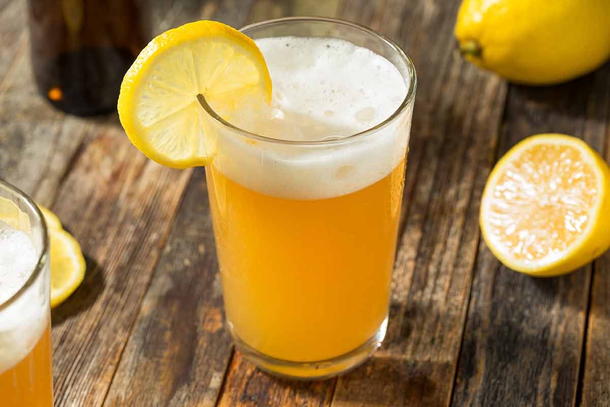 american drinks alcoholic shandy glass on a wooden table with lemons