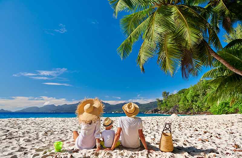 anse soleil seychelles beach family wearing straw hats sitting on the sand