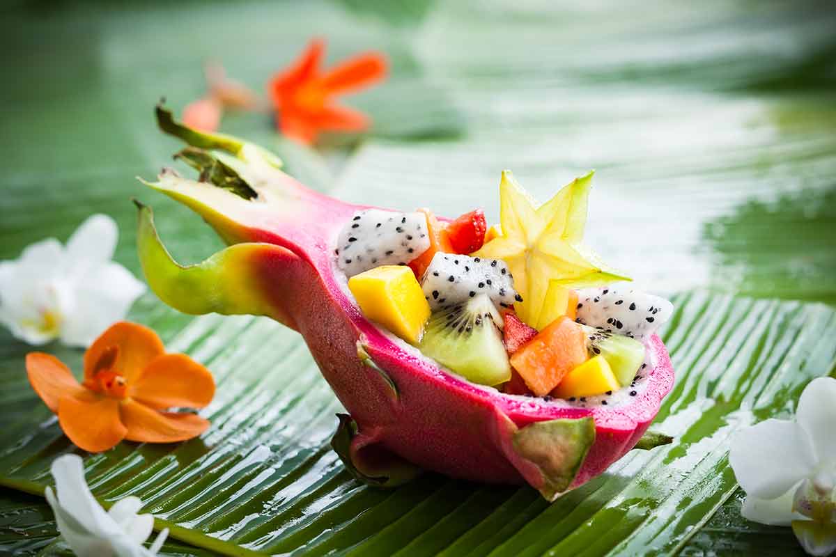 asian fruit salad served in dragon fruit skin on a banan leaf