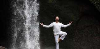 Man Standing In Meditation, Yoga On Rock At Waterfall