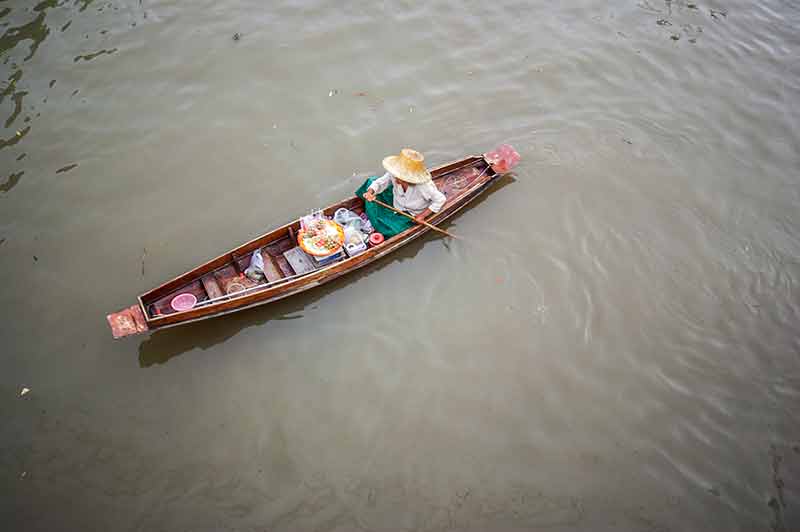 aerial view of local person towing a long boat laden with wares