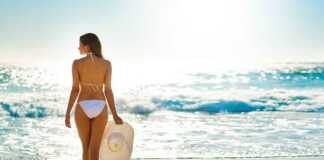 woman in white bikini on beach holding a hat
