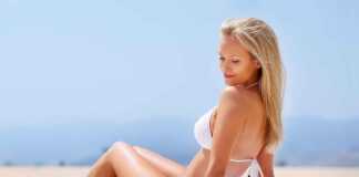 sexy blond in a white bikini sitting on a sandy beach in usa