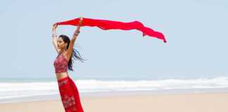 beaches India Indian woman in red sari holding a red scarf above her head on the beach