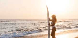 Female surfer holding a surf board on the beach