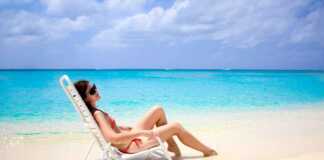 woman in red bikini on a beach lounge next to the ocean