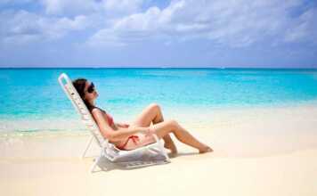 woman in red bikini on a beach lounge next to the ocean