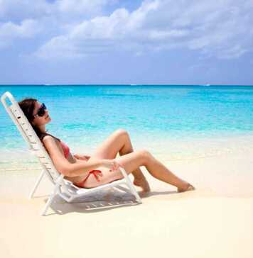 woman in red bikini on a beach lounge next to the ocean