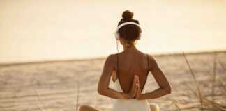 woman in white swimsuit doing yoga on the beach