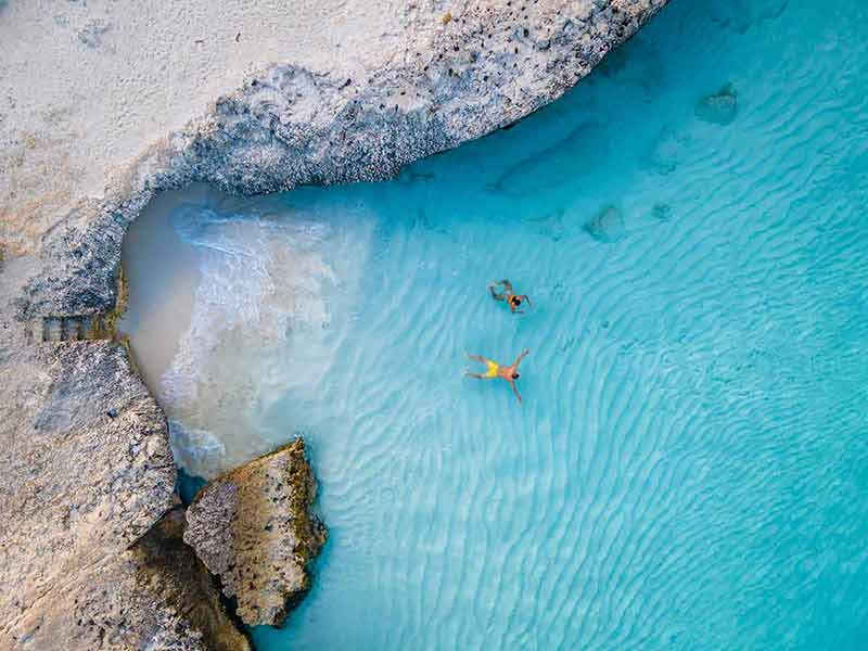 beaches in aruba amn and woman swimming in clear water aerial view