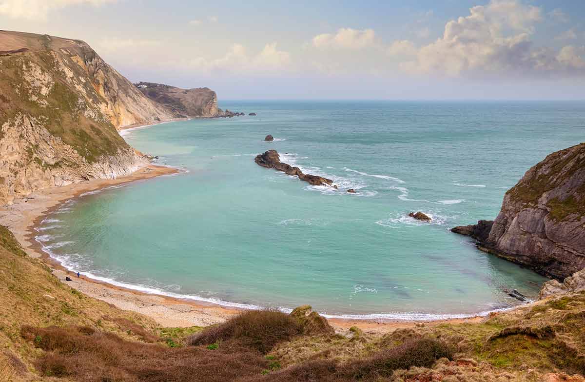 beaches in england Man O'War Cove aerial view with green water and plunging cliffs