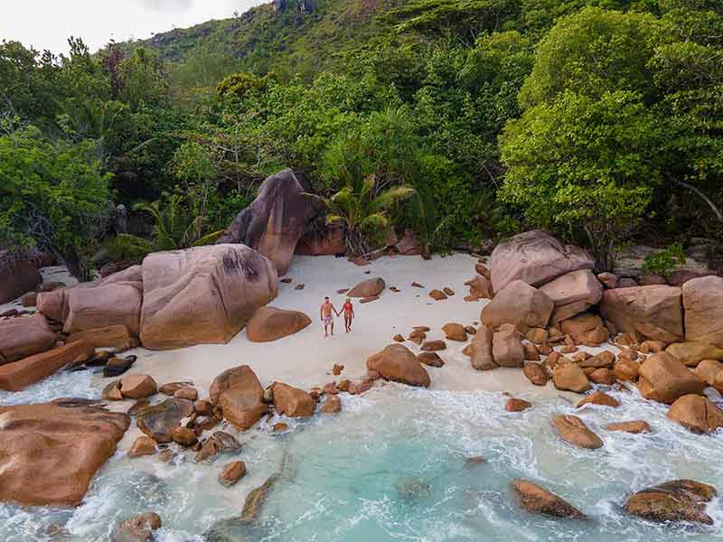beaches in seychelles public man and woman aerial on beach surrounded by rocks