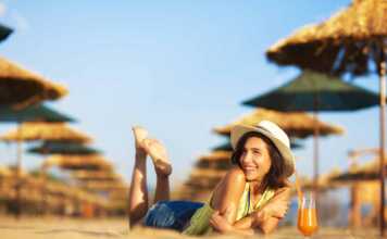 young woman wearing a hat sipping a cocktail at a beach resort