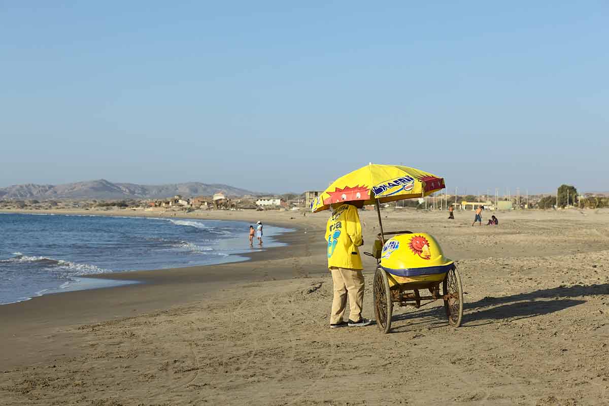beaches near lima peru ice cream vendor with yellow cart and umbrella on Los Organos Beach