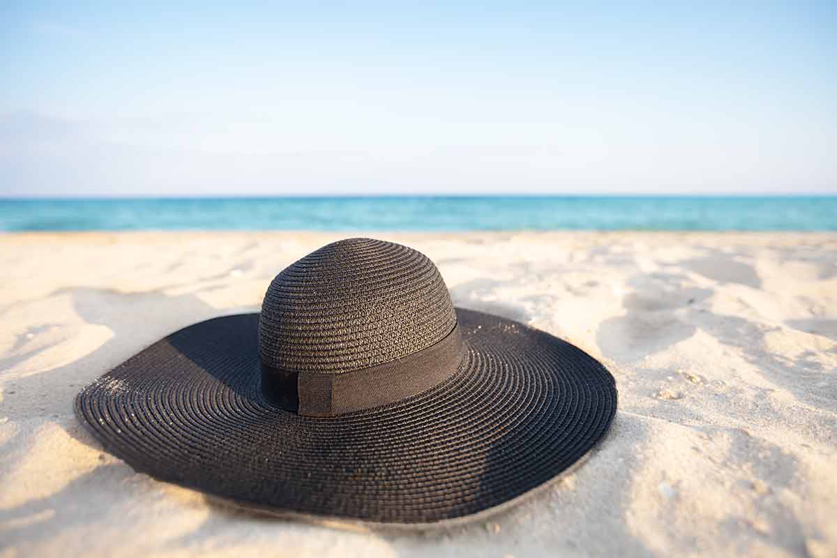 beaches near panama city beach Black hat on a background of the sea. Beach accessory on white sand.
