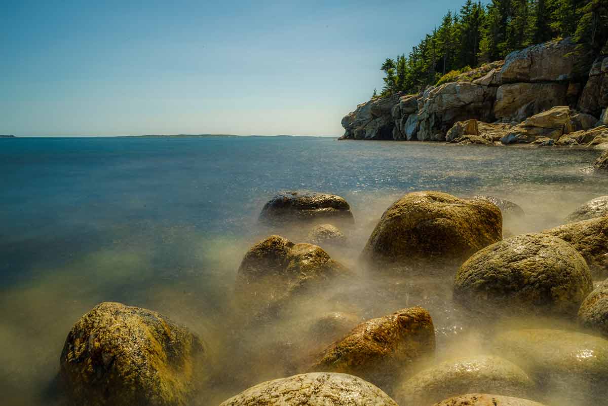beaches near portland maine A time lapse picture of soft, rock-strewn beach against a granite cliff in Maine