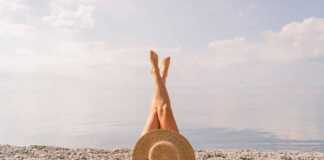 Woman lying on pebble beach with legs in the air