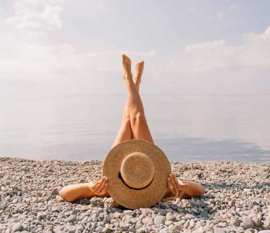 Woman lying on pebble beach with legs in the air