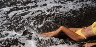 tanned female body in yellow bikini lying on the beach