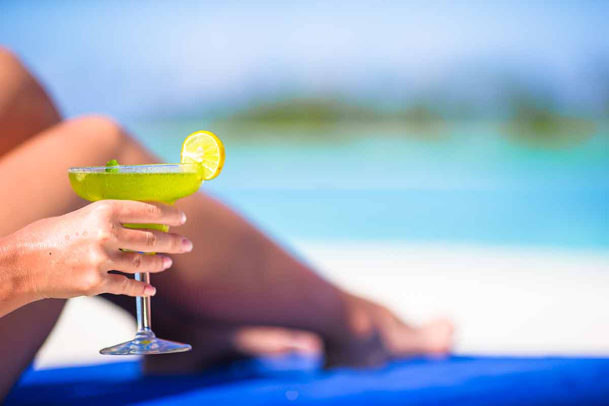 beaches to stay at in malaysia Woman hand with cocktail glass near swimming pool
