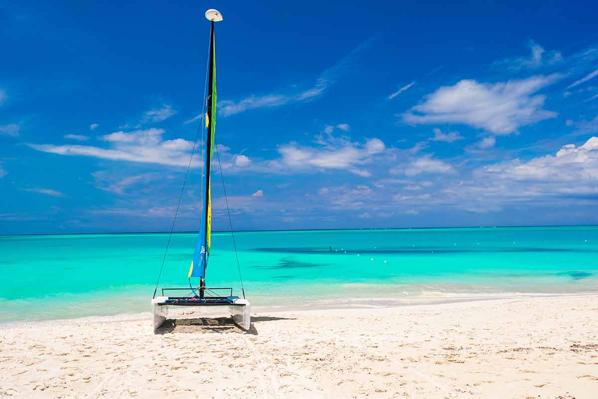 beaches turks and caicos catamaran with colorful sail on caribbean beach