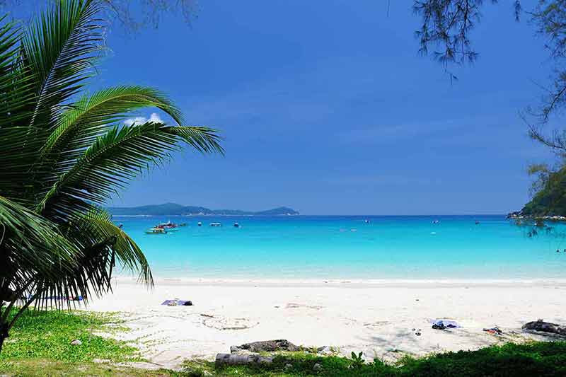 beautiful beaches in malaysia blue water and white sand wtih boats dotted in the ocean